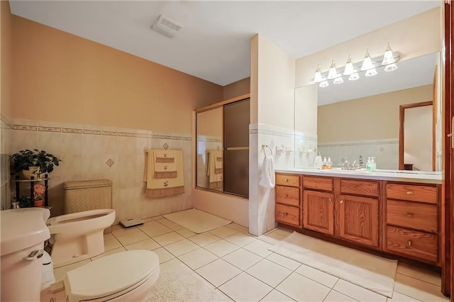 full bathroom with vanity, toilet, tile patterned floors, and tile walls