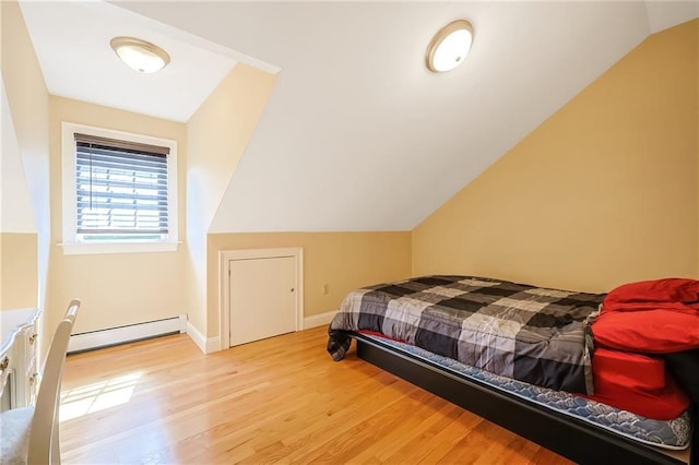 bedroom featuring a baseboard radiator, light hardwood / wood-style flooring, and lofted ceiling