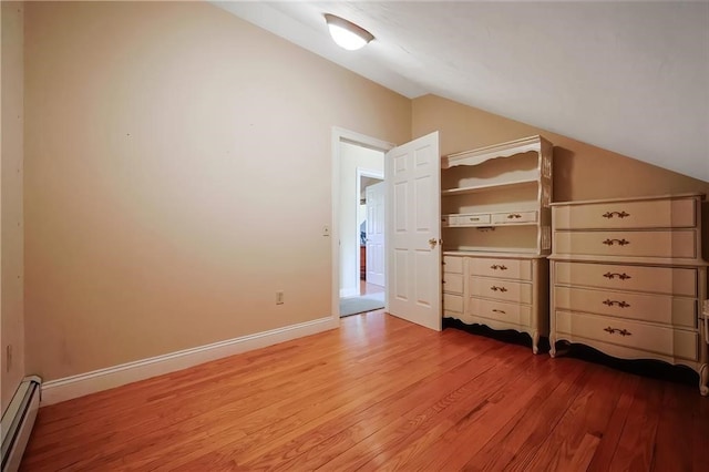 unfurnished bedroom with baseboard heating, lofted ceiling, and light wood-type flooring