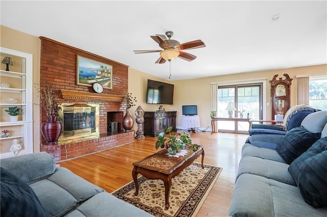 living room with a fireplace, light hardwood / wood-style floors, and ceiling fan