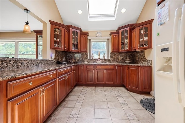 kitchen with tasteful backsplash, vaulted ceiling with skylight, white refrigerator with ice dispenser, and hanging light fixtures