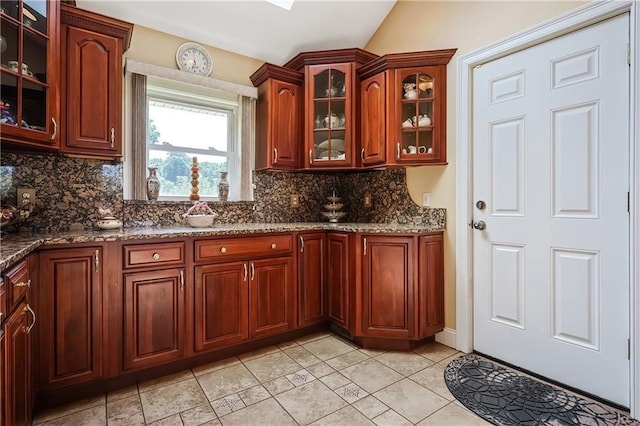 kitchen featuring stone counters, tasteful backsplash, and vaulted ceiling