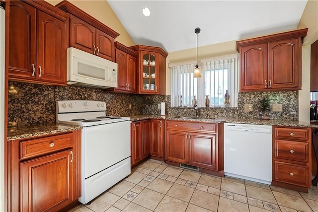 kitchen with hanging light fixtures, vaulted ceiling, dark stone countertops, sink, and white appliances