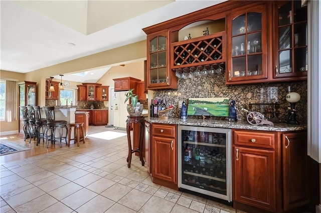 bar with light stone countertops, decorative backsplash, and beverage cooler