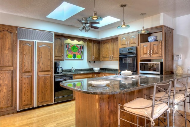 kitchen featuring paneled refrigerator, a skylight, dishwasher, and kitchen peninsula