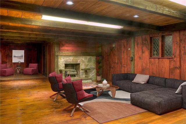 living room with a fireplace, wood walls, light hardwood / wood-style flooring, and beamed ceiling