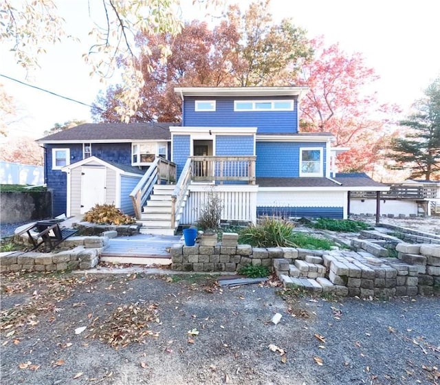 view of front of property featuring a wooden deck, stairs, an outbuilding, and a shed