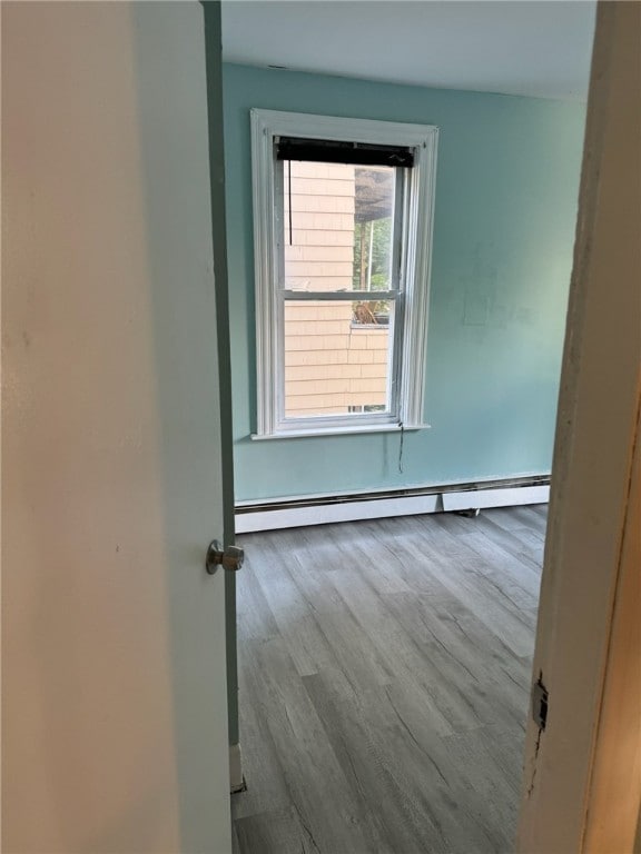 empty room featuring light hardwood / wood-style floors and a baseboard heating unit