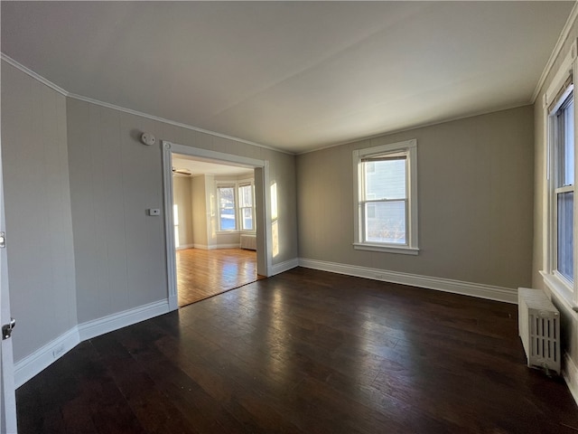 empty room with crown molding, radiator heating unit, plenty of natural light, and dark hardwood / wood-style flooring