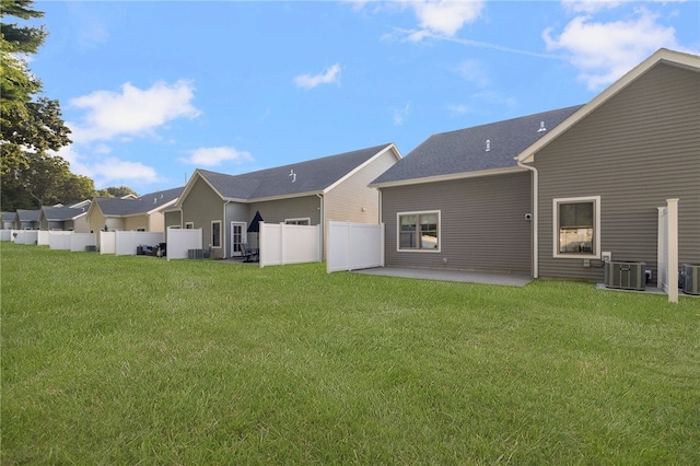 rear view of property featuring a patio, central air condition unit, and a lawn