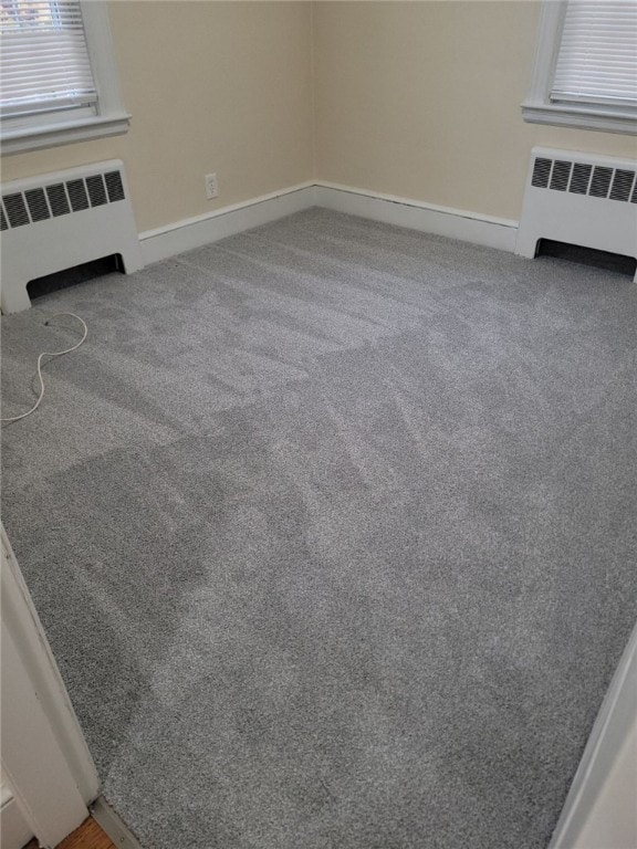 unfurnished living room with radiator heating unit and carpet floors