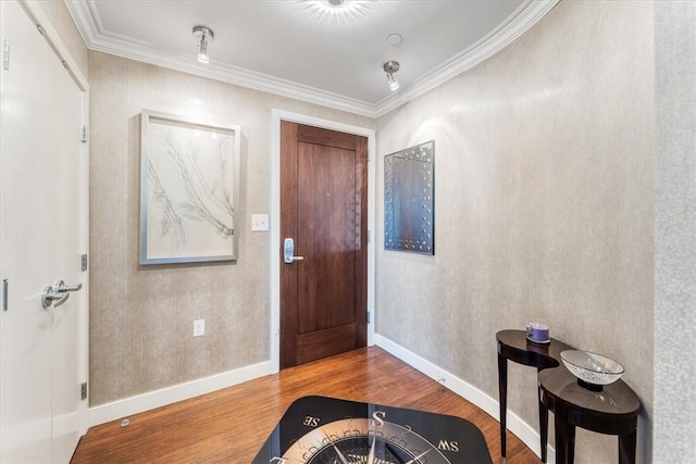 foyer featuring baseboards, crown molding, and wood finished floors