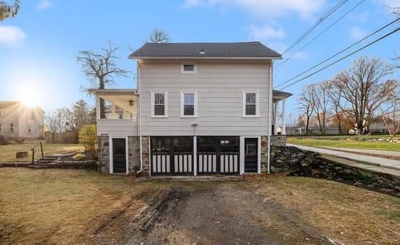 back of property with a yard and a sunroom