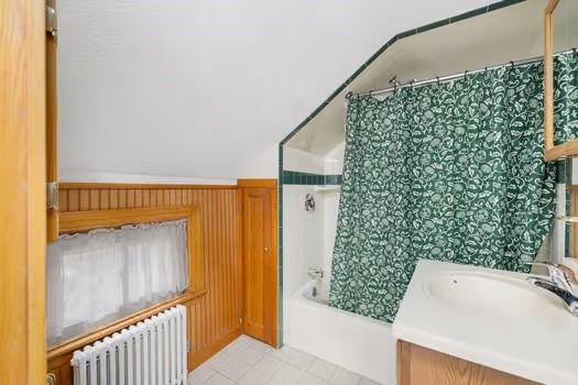 bathroom with shower / bathtub combination with curtain, vanity, and radiator heating unit