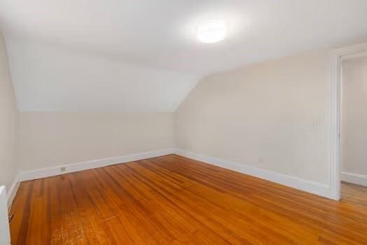 additional living space with hardwood / wood-style flooring and vaulted ceiling