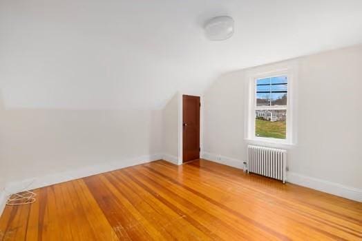 bonus room with radiator heating unit, wood-type flooring, and lofted ceiling