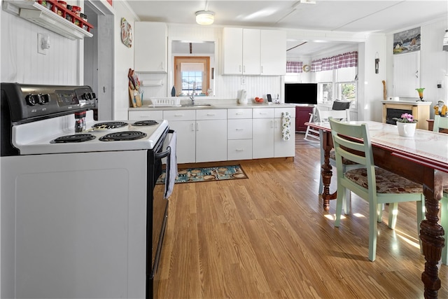 kitchen with white electric range, sink, light wood-type flooring, white cabinetry, and tasteful backsplash