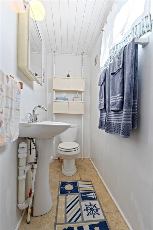 half bath featuring tile patterned floors and toilet