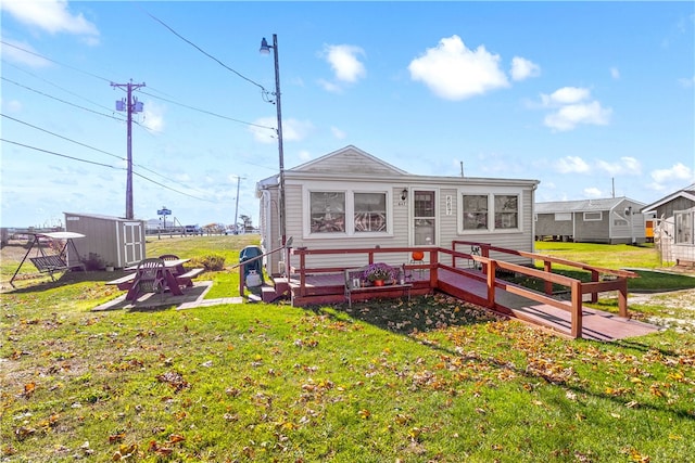 back of property with a patio area, a yard, a storage unit, a deck, and a fire pit