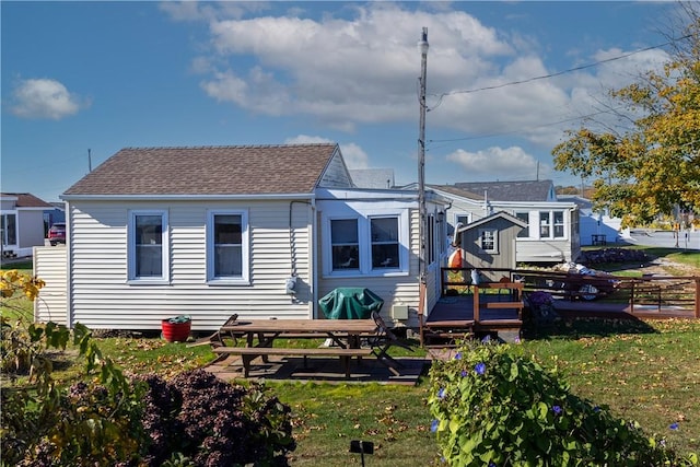 back of house featuring a yard, fence, a wooden deck, and roof with shingles