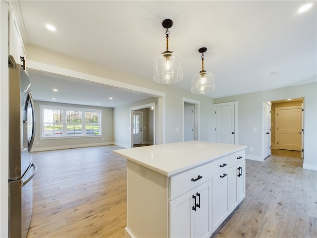 kitchen with a kitchen island, light hardwood / wood-style flooring, white cabinets, and decorative light fixtures