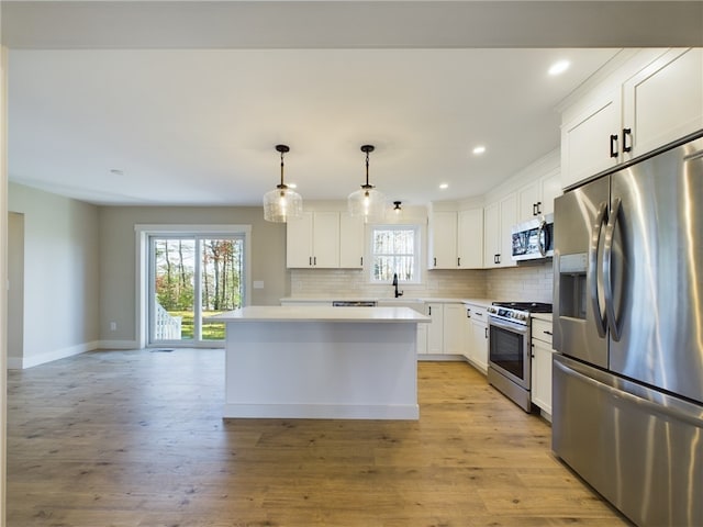 kitchen featuring appliances with stainless steel finishes, a kitchen island, white cabinetry, tasteful backsplash, and hanging light fixtures