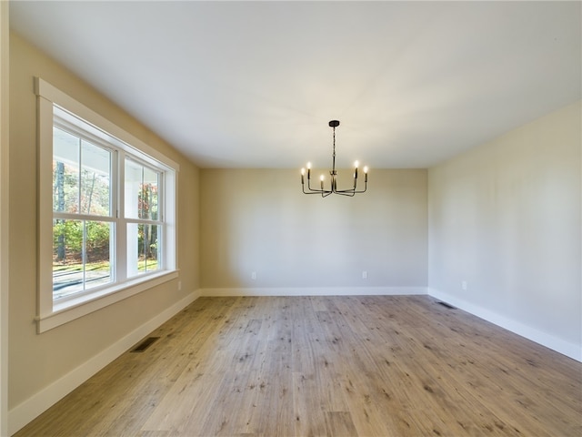 spare room with a notable chandelier and light hardwood / wood-style floors