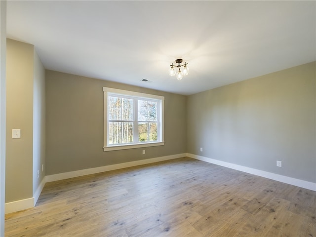 empty room with a chandelier and light hardwood / wood-style flooring