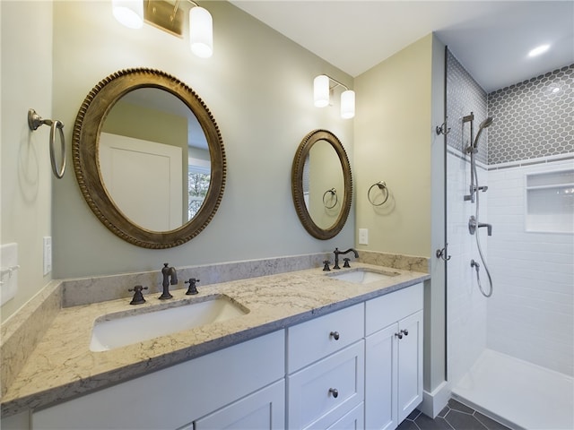 bathroom featuring tile patterned flooring, a tile shower, and vanity