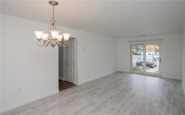 empty room featuring a chandelier and light wood-type flooring