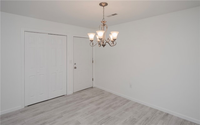 empty room featuring light hardwood / wood-style flooring and an inviting chandelier