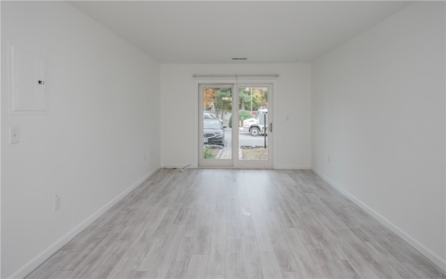 unfurnished room with electric panel and light wood-type flooring