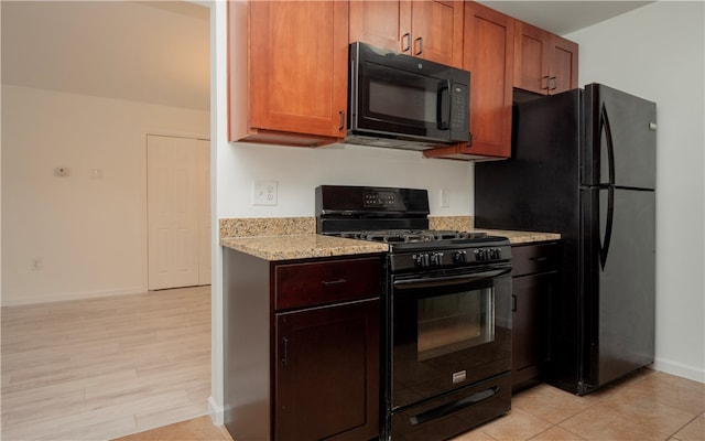 kitchen with black appliances, light stone counters, and light wood-type flooring