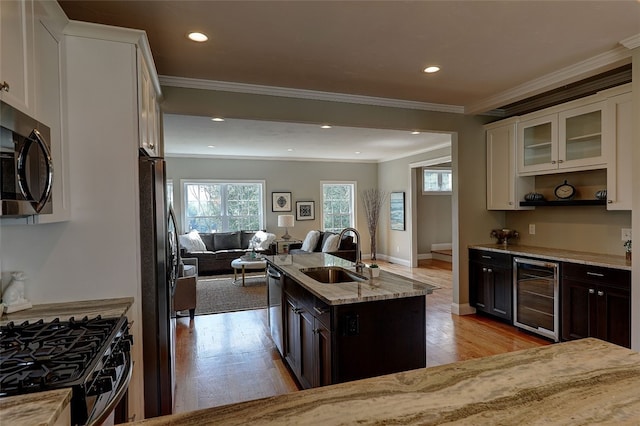 kitchen featuring appliances with stainless steel finishes, sink, white cabinetry, dark brown cabinetry, and beverage cooler