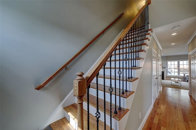 stairs with crown molding and wood-type flooring