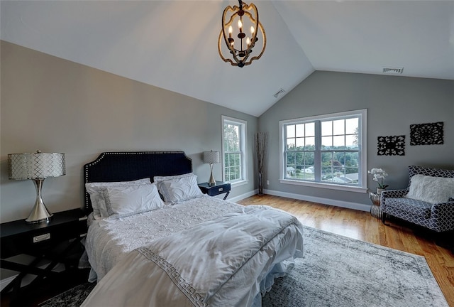 bedroom with a notable chandelier, lofted ceiling, and hardwood / wood-style floors