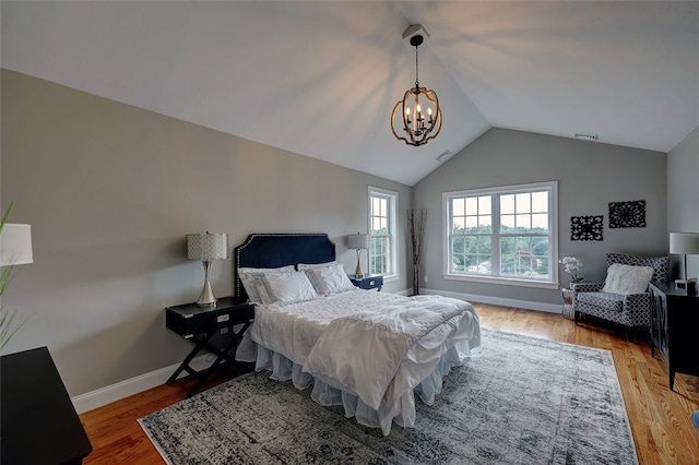 bedroom featuring hardwood / wood-style flooring, a chandelier, and vaulted ceiling