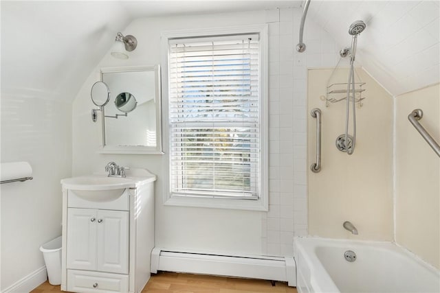 bathroom with a baseboard radiator, hardwood / wood-style floors, vaulted ceiling, vanity, and tiled shower / bath