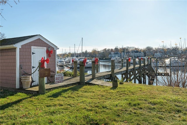 view of dock with a yard and a water view