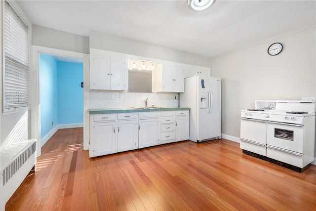 kitchen featuring white appliances, white cabinetry, radiator, and sink