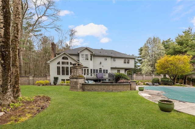 rear view of property featuring a pool side deck and a lawn