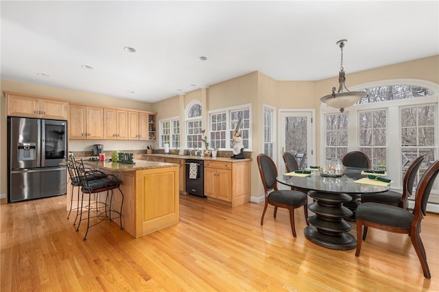 kitchen featuring stone counters, stainless steel fridge with ice dispenser, decorative light fixtures, light hardwood / wood-style flooring, and light brown cabinets