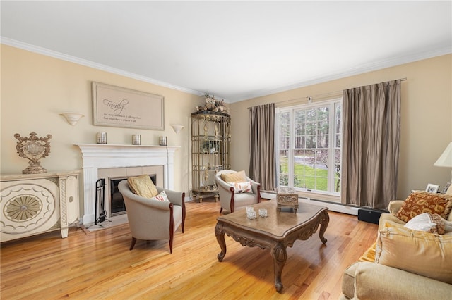 sitting room with ornamental molding, light wood-type flooring, and a tile fireplace