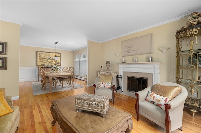 living room with a tile fireplace, crown molding, light wood-type flooring, and a baseboard radiator