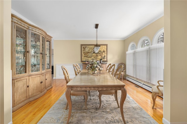 dining space featuring crown molding, baseboard heating, and light wood-type flooring