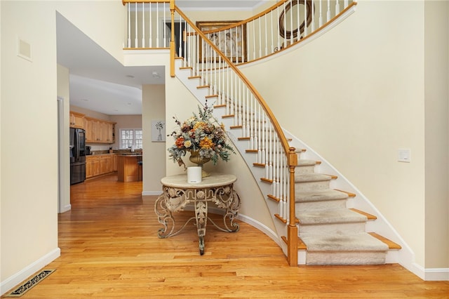 staircase featuring hardwood / wood-style flooring and a high ceiling