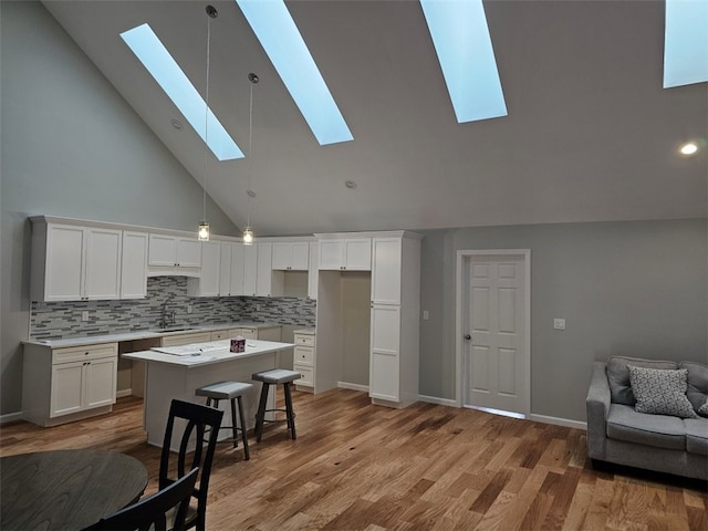 kitchen with light hardwood / wood-style flooring, white cabinets, a center island, and high vaulted ceiling