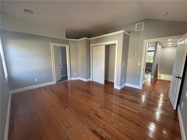 unfurnished bedroom featuring a closet, dark wood-type flooring, and vaulted ceiling