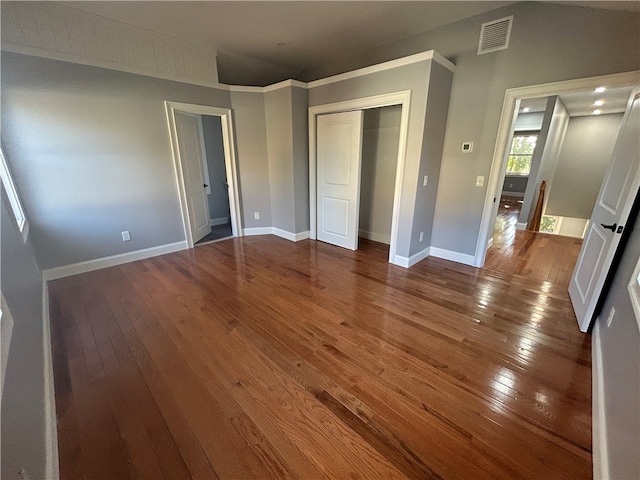 unfurnished bedroom featuring a closet, ornamental molding, and hardwood / wood-style floors