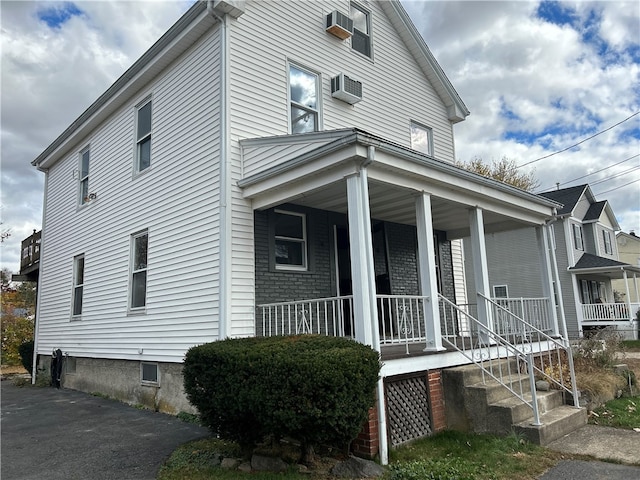 view of side of home featuring a wall mounted AC and a porch